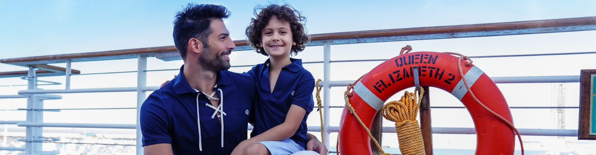 Kid sitting on dad's lap in a sailing aboat